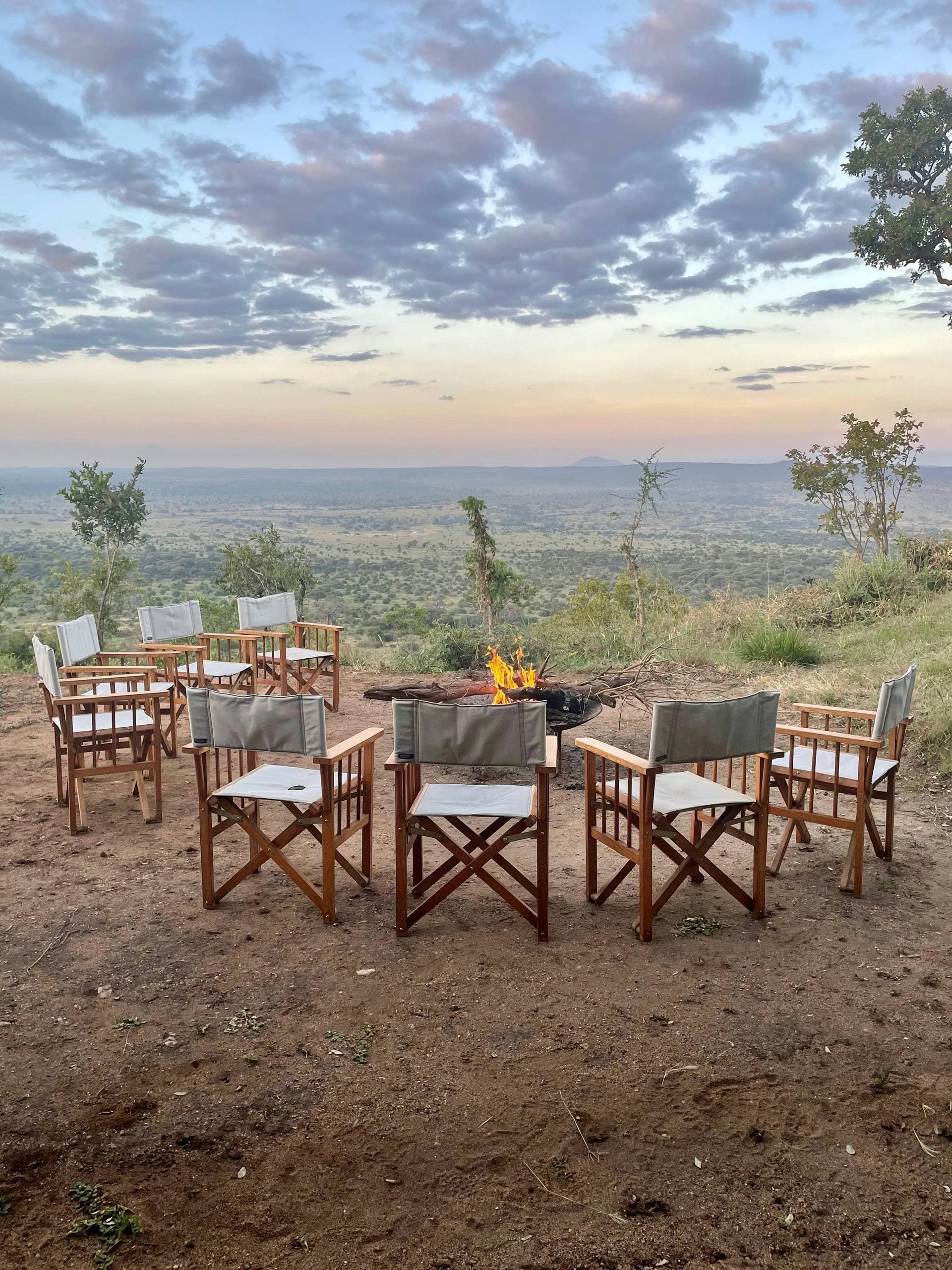 Safari chairs arranged around a lantern-lit fire